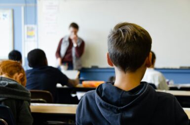 photo d'un enfant de dos, en classe, qui regarde le tableau